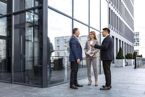 réunion de Trois réussi affaires personnes, diverse rêver équipe homme et femme à l'extérieur Bureau bâtiment, salutation et tremblement mains, expérimenté professionnels spécialistes dans affaires costume parlant photo