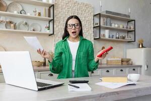 une inquiet femme séance à Accueil avec portable et documents. problèmes avec comptes, crédit photo