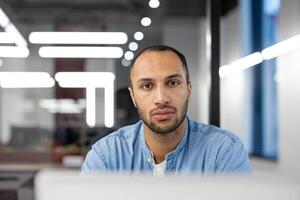 une Jeune homme concentré sur le sien travail dans une contemporain bureau, incarner le esprit de professionnalisme et dévouement dans une entreprise environnement. photo