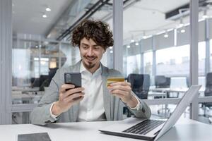 expérimenté Jeune adulte homme d'affaire dans une moderne bureau, souriant comme il les usages une téléphone. spectacles multitâche, se concentrer, et une positif émotif État. photo