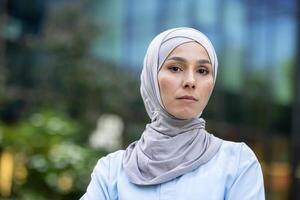 une moderne musulman femme portant hijab des stands en toute confiance dans un Urbain paramètre, exsudant responsabilisation et diversité. photo