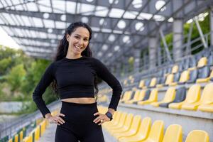 en forme et content femme portant athlétique porter des stands en toute confiance dans une stade avec une sourire, exsudant santé et positivité. photo