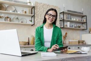 Jeune magnifique femme dans des lunettes et décontractée vert chemise souriant et à la recherche à caméra photo