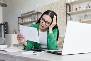 affligé Jeune femme asseoir sur canapé à Accueil lis mal négatif nouvelles dans papier correspondance photo