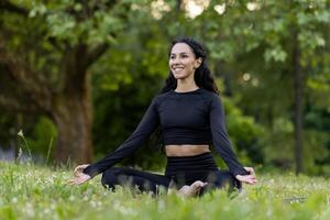 Jeune femme immergé dans méditation, performant yoga dans une paisible vert parc, incorporant santé et pleine conscience. photo