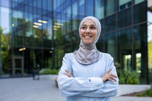 professionnel musulman femme dans une hijab des stands en toute confiance à l'extérieur un Urbain entreprise bâtiment, dépeindre responsabilisation et diversité. photo