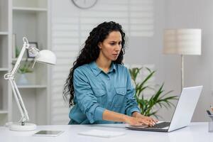 professionnel femelle exécutif engagé dans concentration tandis que en utilisant portable à une Bien organisé lieu de travail avec intérieur les plantes. photo