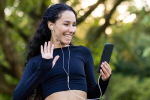 un actif femme pauses pour une casser, en utilisant sa téléphone tandis que sur une faire des exercices dans une luxuriant vert parc. photo