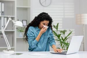 mauvais Jeune femme d'affaires en utilisant une tissu tandis que travail à sa Bureau bureau, montrant symptômes de une froid. photo