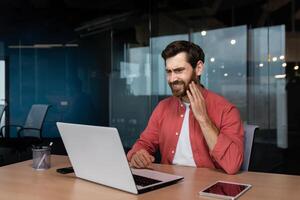 Bureau ouvrier a une mal aux dents, une malade homme d'affaire travaux à l'intérieur le Bureau avec une ordinateur portable, une homme a une mal aux dents à le lieu de travail. photo