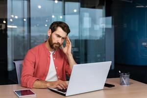 malade homme à lieu de travail, mature homme d'affaire a sévère mal de tête, patron dans chemise travaux à l'intérieur Bureau avec portable. photo