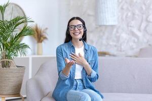 une femme est ayant une éloigné emploi entretien en ligne. séance à Accueil avec une portable dans une casque photo