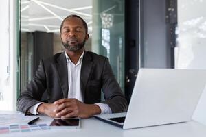 équilibré et calme homme à lieu de travail à l'intérieur bureau, homme d'affaire méditer avec fermé yeux en pensant et visualisation futur projets et des plans financier stratégies, patron à l'intérieur Bureau avec portable. photo