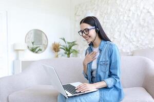 une femme est ayant une éloigné emploi entretien en ligne. séance à Accueil avec une portable dans une casque photo