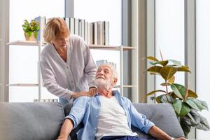 Sénior couple dans le vivant chambre, personnes âgées homme et une femme relaxant sur une confortable canapé à maison, content famille concepts photo