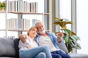 Sénior couple dans le vivant chambre, personnes âgées homme et une femme relaxant sur une confortable canapé à maison, content famille concepts photo