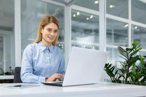 une concentré professionnel femme engage avec sa portable dans une brillant, contemporain Bureau paramètre, incorporant Efficacité et dévouement. photo