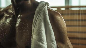 une homme séchage de avec une serviette perles de transpiration visible sur le sien peau après une longue session dans le sauna. photo