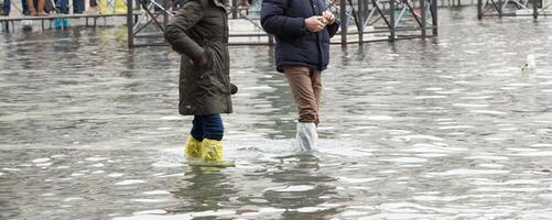 proche en haut de jambes avec bottes dû à le haute l'eau dans venise. photo