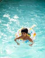 content Indien garçon nager dans une piscine, enfant portant nager costume le long de avec air tube pendant chaud été les vacances, les enfants garçon dans gros nager bassin. photo