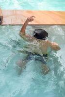 content Indien garçon nager dans une piscine, enfant portant nager costume le long de avec air tube pendant chaud été les vacances, les enfants garçon dans gros nager bassin. photo