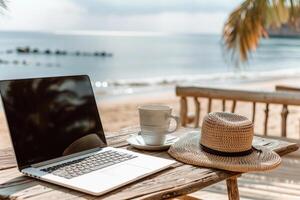 une portable est ouvert sur une table suivant à une paille chapeau et une tasse photo