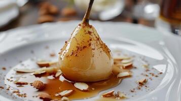 une délicat poché poire servi avec une infusé à la cannelle sirop et une saupoudrer de grillé amandes photo