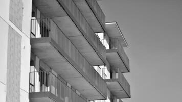 fragment de le bâtiments façade avec les fenêtres et balcons. moderne appartement bâtiments sur une ensoleillé journée. façade de une moderne Résidentiel bâtiment. noir et blanche. photo