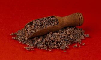 râpé Chocolat dans en bois scoop isolé sur rouge Couleur arrière-plan, fermer photo
