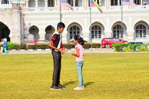 Kuala lumpur, Malaisie sur mai 21, 2023. un plus âgée frère et une plus jeune sœur sont en jouant sur le dataran Merdeka champ photo