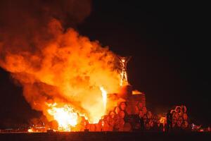 ardent flamber engloutit en bois structure dans désert nuit scène photo