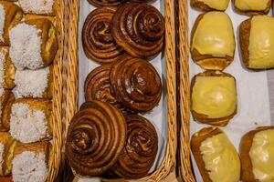 une lot de sucré des pâtisseries dans paniers sur le compteur dans le nourriture magasin. boulangerie sur le buffet tableau. affaires petits déjeuners et restauration à événements. divers pain type sur étagère. fermer. sélectif se concentrer. photo