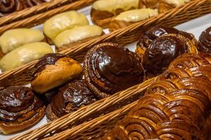 une lot de sucré des pâtisseries dans paniers sur le compteur dans le nourriture magasin. boulangerie sur le buffet tableau. affaires petits déjeuners et restauration à événements. divers pain type sur étagère. fermer. sélectif se concentrer. photo