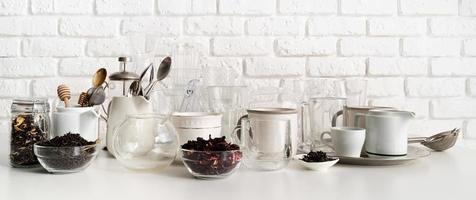 tasses et vaisselle en céramique et en verre sur la table sur fond de mur de briques blanches photo
