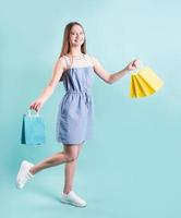 Happy young woman with shopping bags isolé sur fond bleu