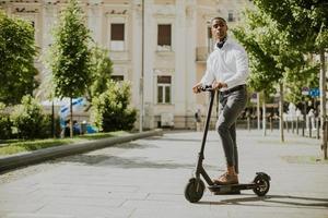 Jeune afro-américain à l'aide d'un scooter électrique dans une rue
