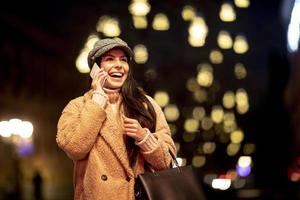 Jolie jeune femme utilisant son téléphone portable dans la rue au moment de Noël photo