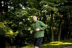 jeune homme athlétique qui court tout en faisant de l'exercice dans un parc verdoyant ensoleillé photo