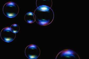 bulles bleues transparentes motif de savon superposition de particules abstraites éclaboussures d'eau sur fond noir. photo