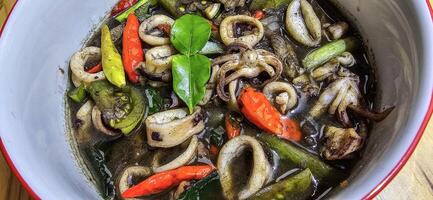 indonésien Accueil cuisine menu, sautés calamar avec noir encre sauce avec épicé assaisonnement appelé tumis cum Hitam, comprenant le Chili, gingembre, et citron vert feuille photo