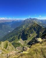 captivant vue de le Caucase montagnes baigné dans lumière du soleil, avec verdoyant pistes et loin pics contre une vibrant bleu ciel photo