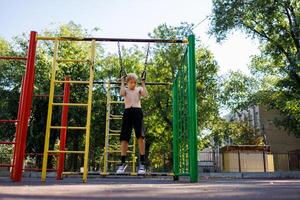 rue faire des exercices sur une horizontal bar dans le école parc. photo