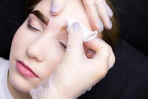 dans le mains de le Maître est une coton éponge avec lequel il supprime le vestiges de peindre de peint les sourcils photo