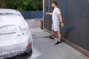 partie de le voiture est couvert avec mousse, le la personne dans le Contexte est appliquant mousse à le auto. une voiture à une soi un service voiture laver. photo