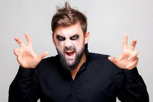 effrayant style mort-vivant maquillage pour Halloween sur une barbu homme qui spectacles gestes photo