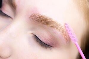 macro la photographie de le œil, le sourcil de lequel est combiné avec une brosse, le Cheveux sont posé après le stratification composition photo