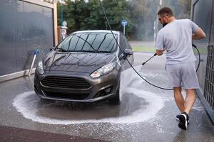 à une voiture laver, une homme lavages le sien auto. une voiture à une soi un service voiture laver. photo