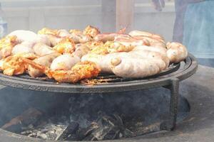 frit saucisses et poulet ailes sur barbecue gril dans le village. friture Viande sur ouvert Feu. barbecue fête sur arrière-cour de pays maison cabine. rue nourriture festival. Accueil cuisine Extérieur. pique-nique temps photo