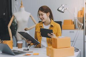 les femmes d'affaires de PME asiatiques utilisent un ordinateur portable pour vérifier les boîtes d'expédition en ligne des commandes des clients à la maison. démarrage d'une petite entreprise entrepreneur PME indépendant. entreprise en ligne, concept de travail à domicile. photo