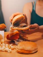 vite nourriture, gens et mauvais pour la santé en mangeant concept - proche en haut de femme mains en portant Hamburger ou cheeseburger photo